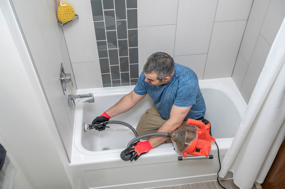 Plumber drain cleaning a bathtub with a plumbers snake Venice, FL